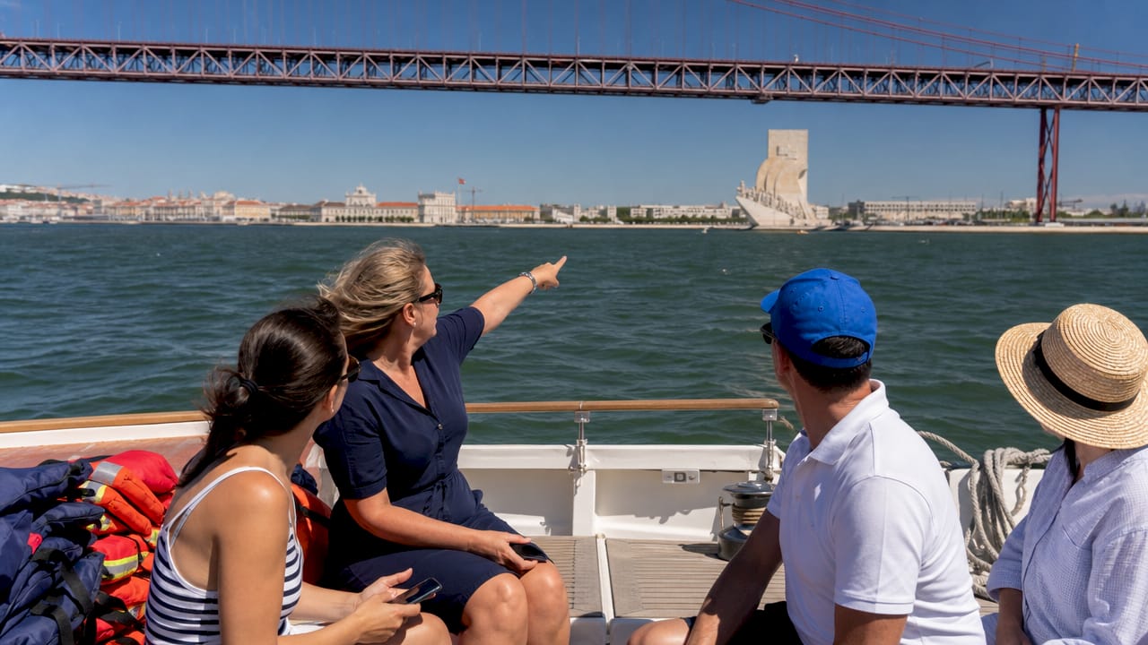 Passengers viewing Belém Tower from a sailboat