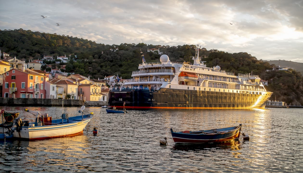 Coastal cruise ship docked at harbor with village