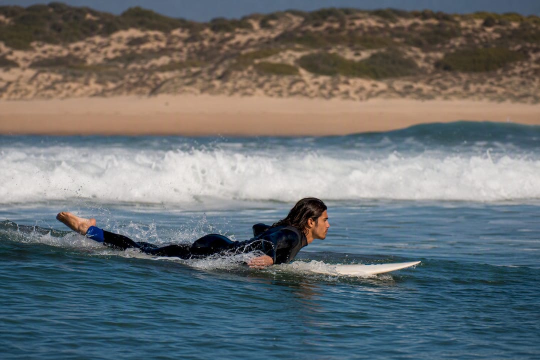 Surfer paddling through Guincho waves
