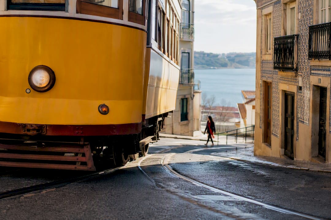Vintage tram rounding Lisbon hillside above Tagus