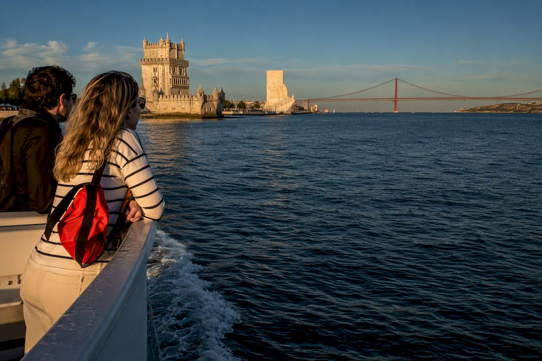 Passengers viewing Lisbon landmarks from the Tagus