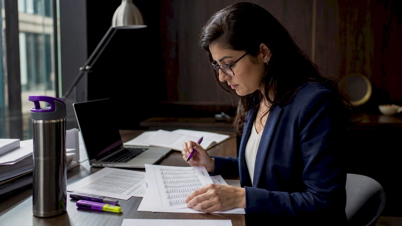 Researcher reviewing printed structured table at desk