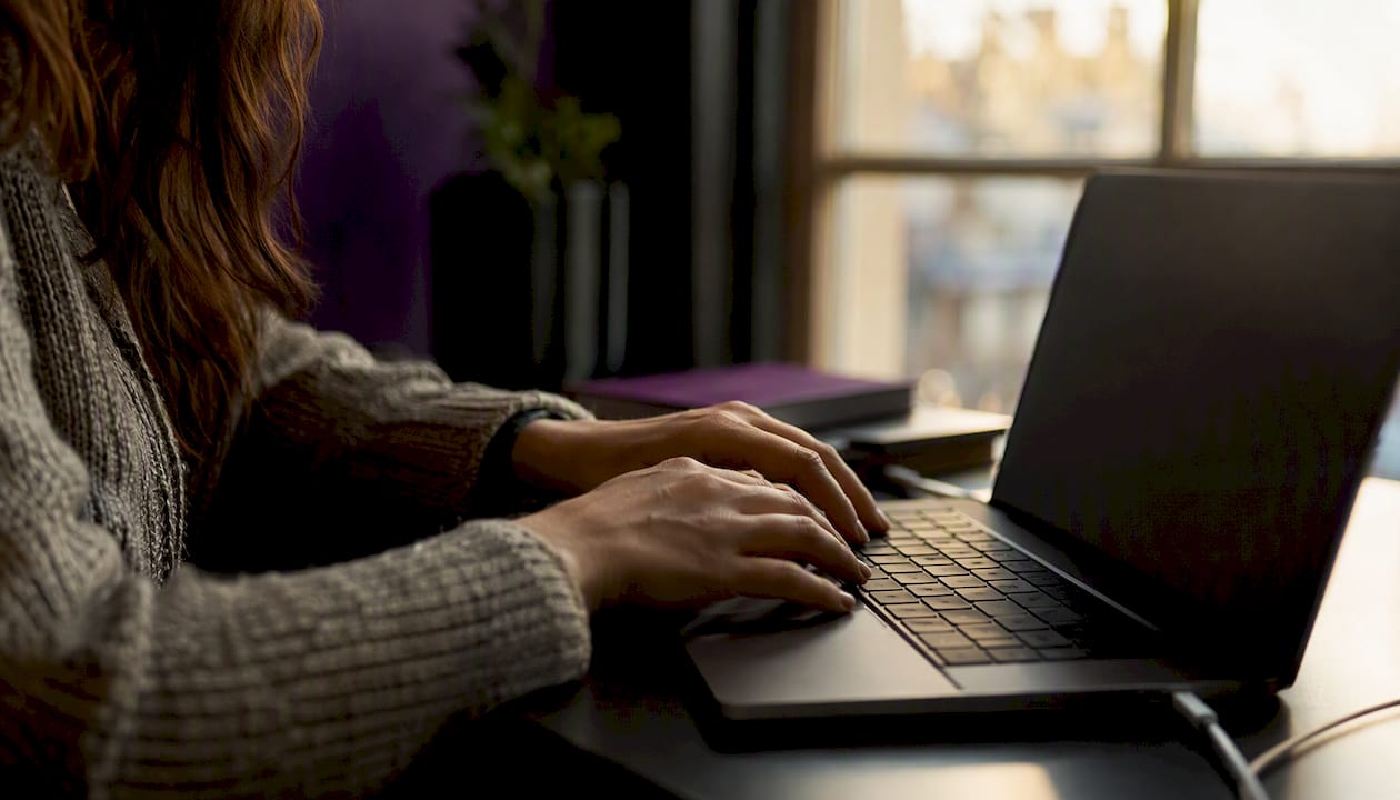 Hands typing reflexive journal entry on laptop keyboard