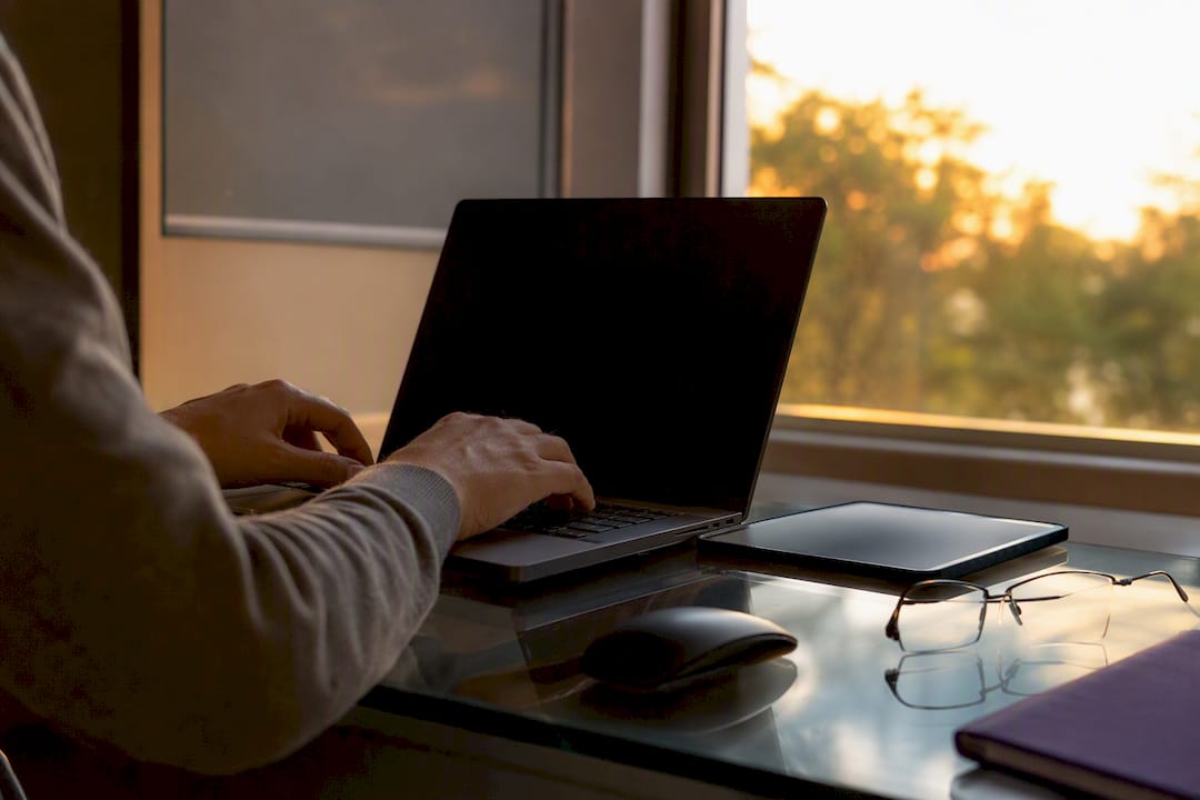 Hands near a dark laptop and tablet in research workspace