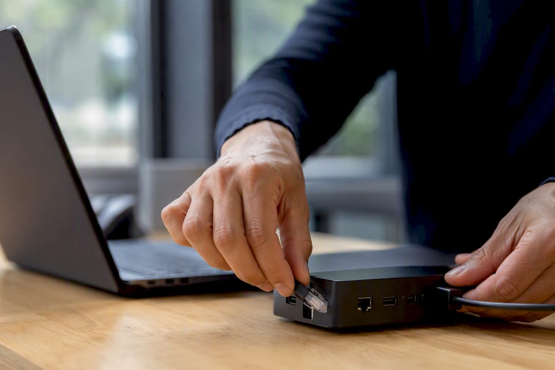 Hands connecting network cable on desk