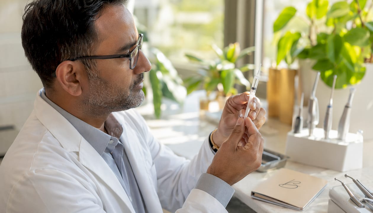 Dentist holding syringe with whitening gel