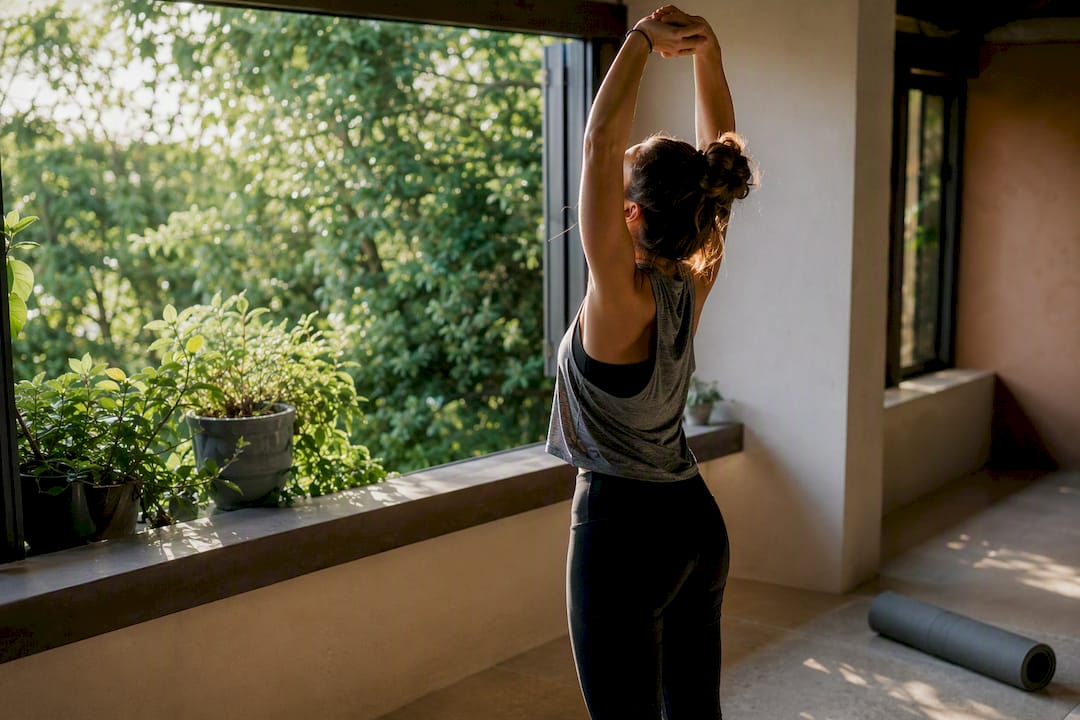 Person stretching indoors near window light