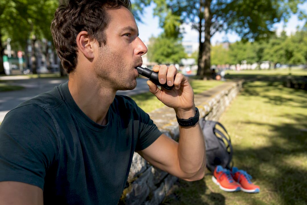Athlete inhaling oxygen with mouthpiece outdoors
