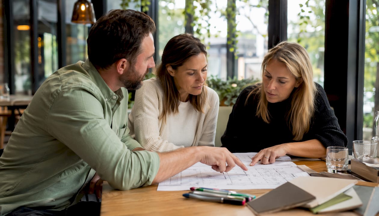 Clients consulting builder over plans in office