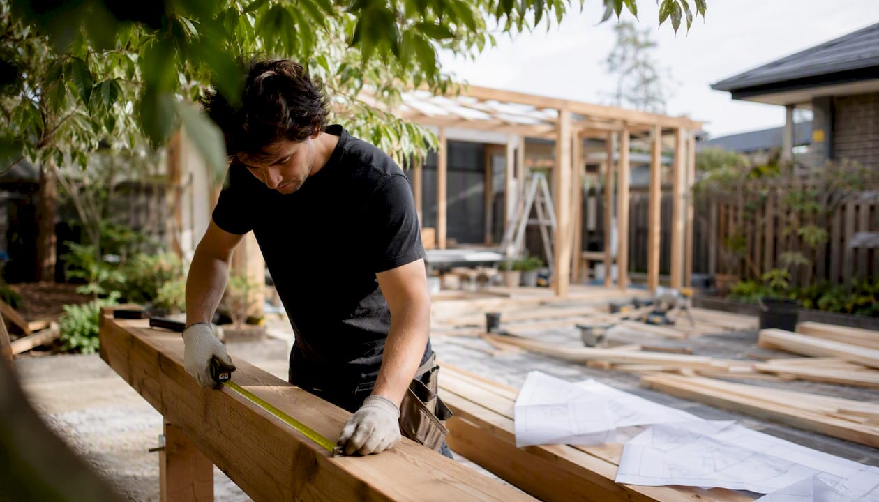 Worker measuring timber beam at Melbourne home site