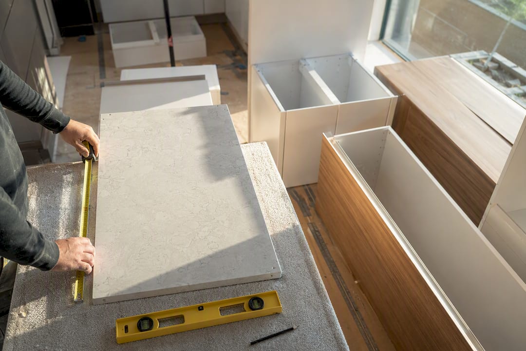 Hands measuring stone benchtop in Melbourne kitchen renovation