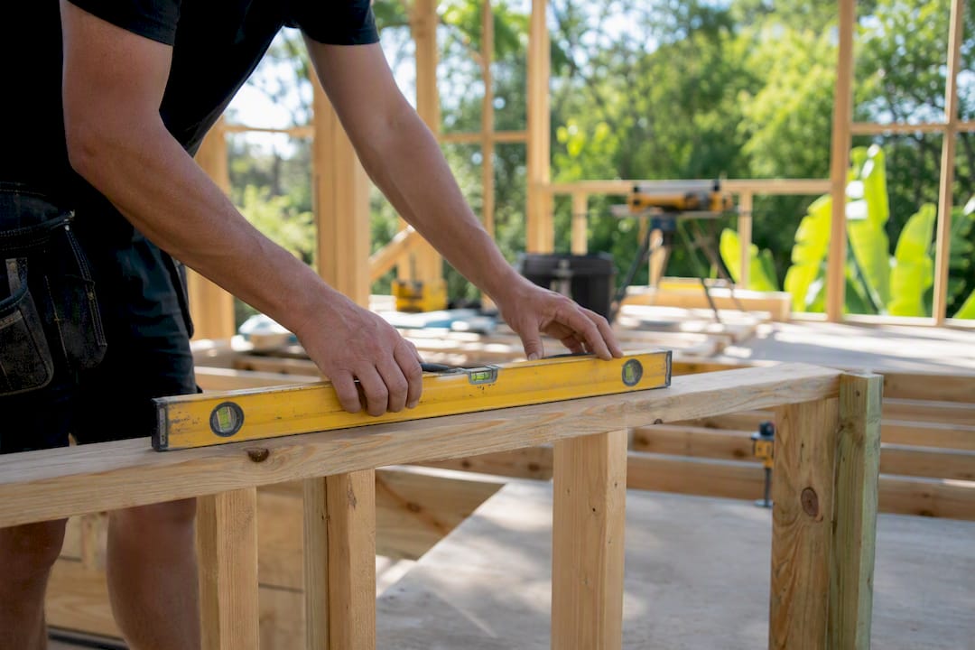 Builder using spirit level on timber frame