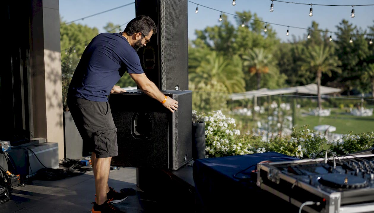 DJ technician setting up PA speakers on stage