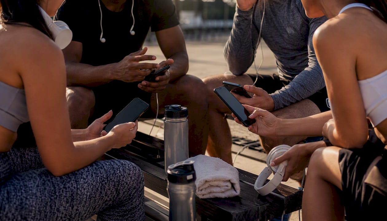 Diverse athletes with music devices preparing playlists