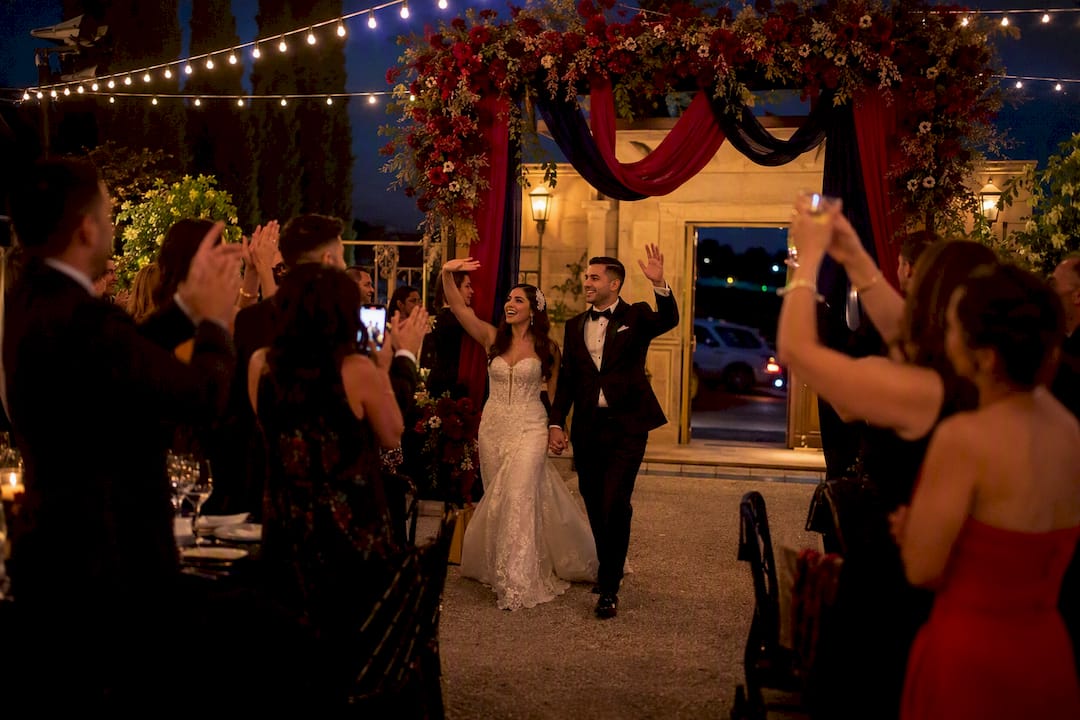 Wedding couple entering reception amid cheering guests