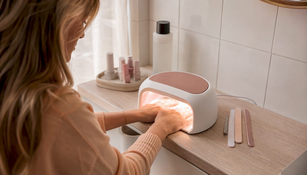 Handen worden onder een UV-lamp gehouden om gelnagels uit te harden.