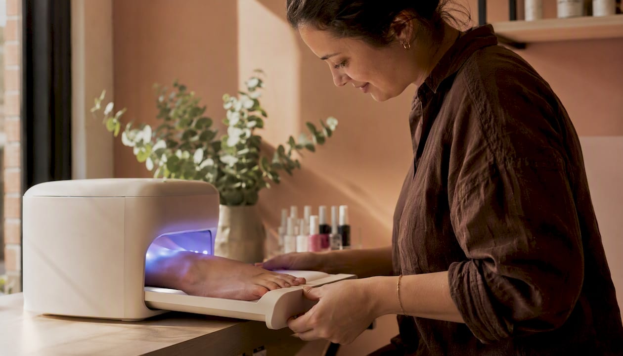 Een hand plaatst voorzichtig de tenen in het uitneembare bakje van de LED UV lamp.