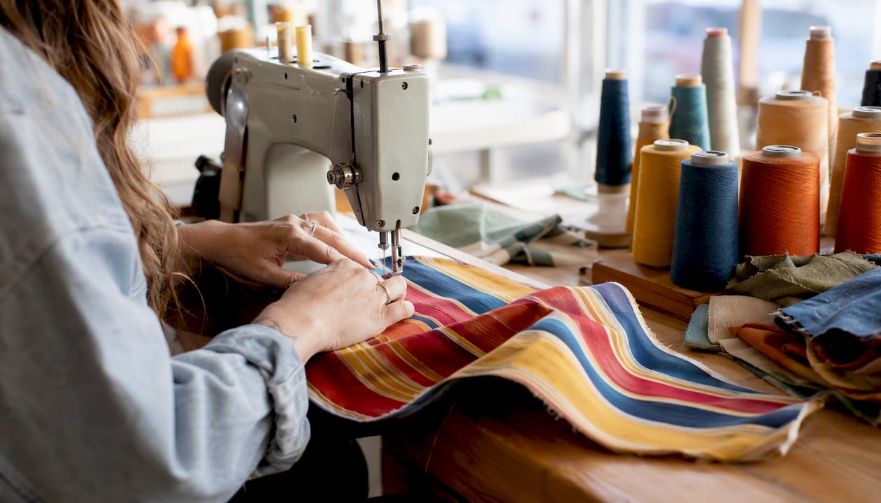 Hands sewing eco-conscious Colorado apparel