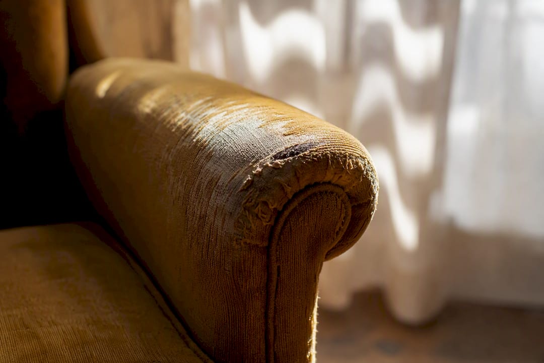 Worn upholstery fabric on vintage armchair armrest