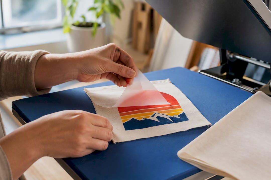 Hands lifting transfer from heat press