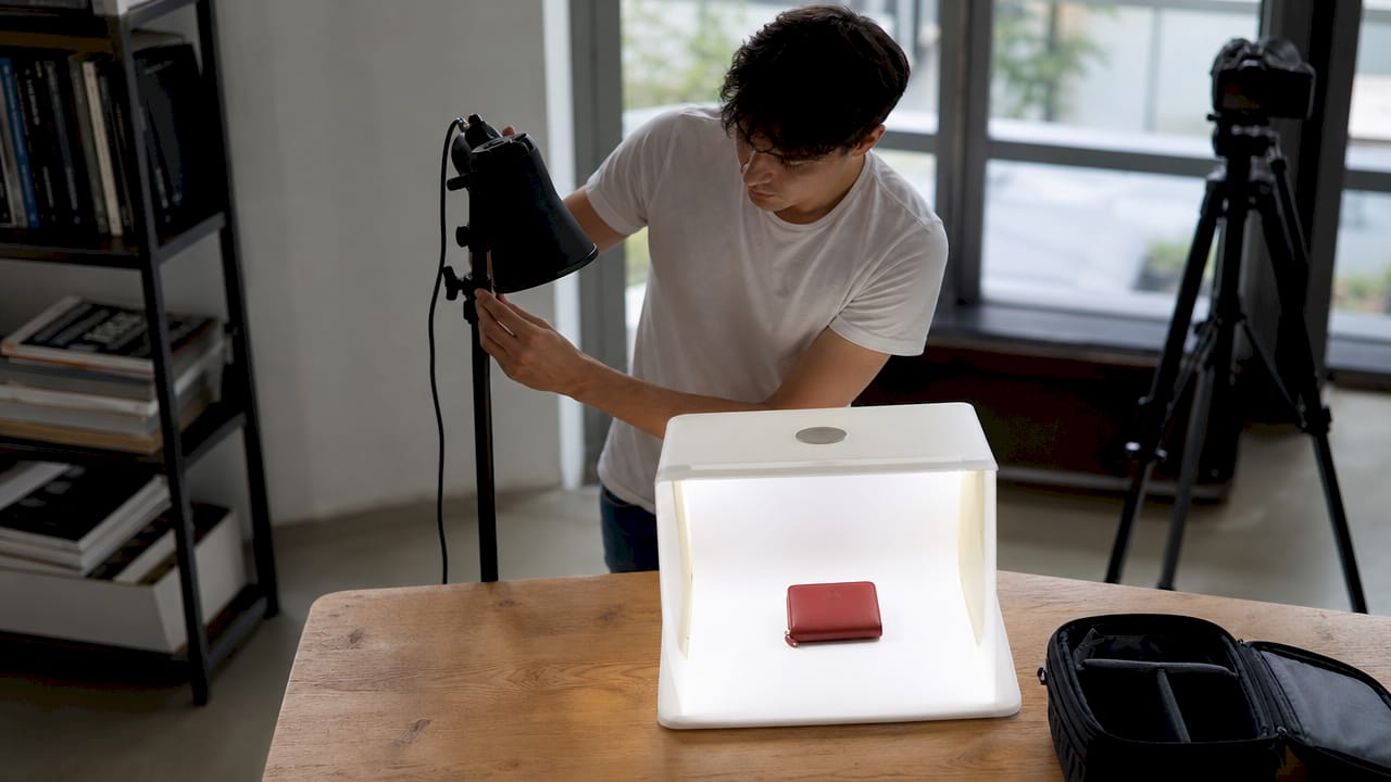 Eine Person richtet im Fotostudio die Beleuchtung für ein Produkt ein.