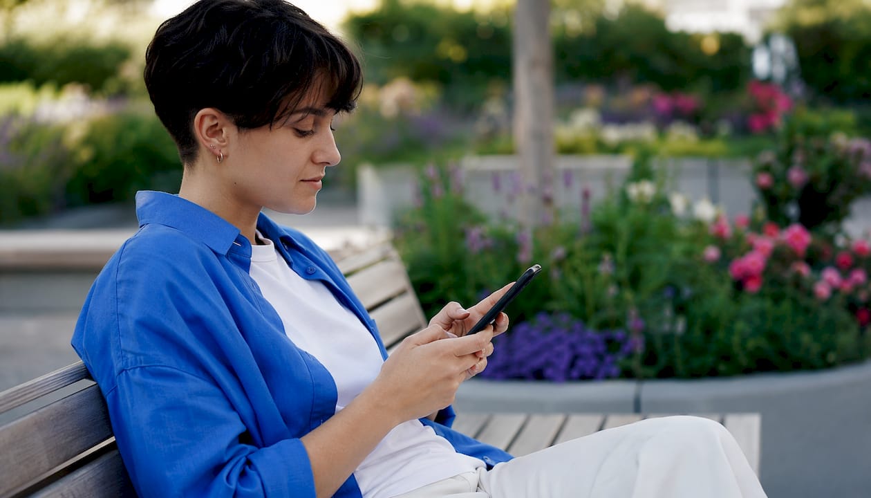Eine Frau füllt im Café ein Formular auf ihrem Smartphone aus.