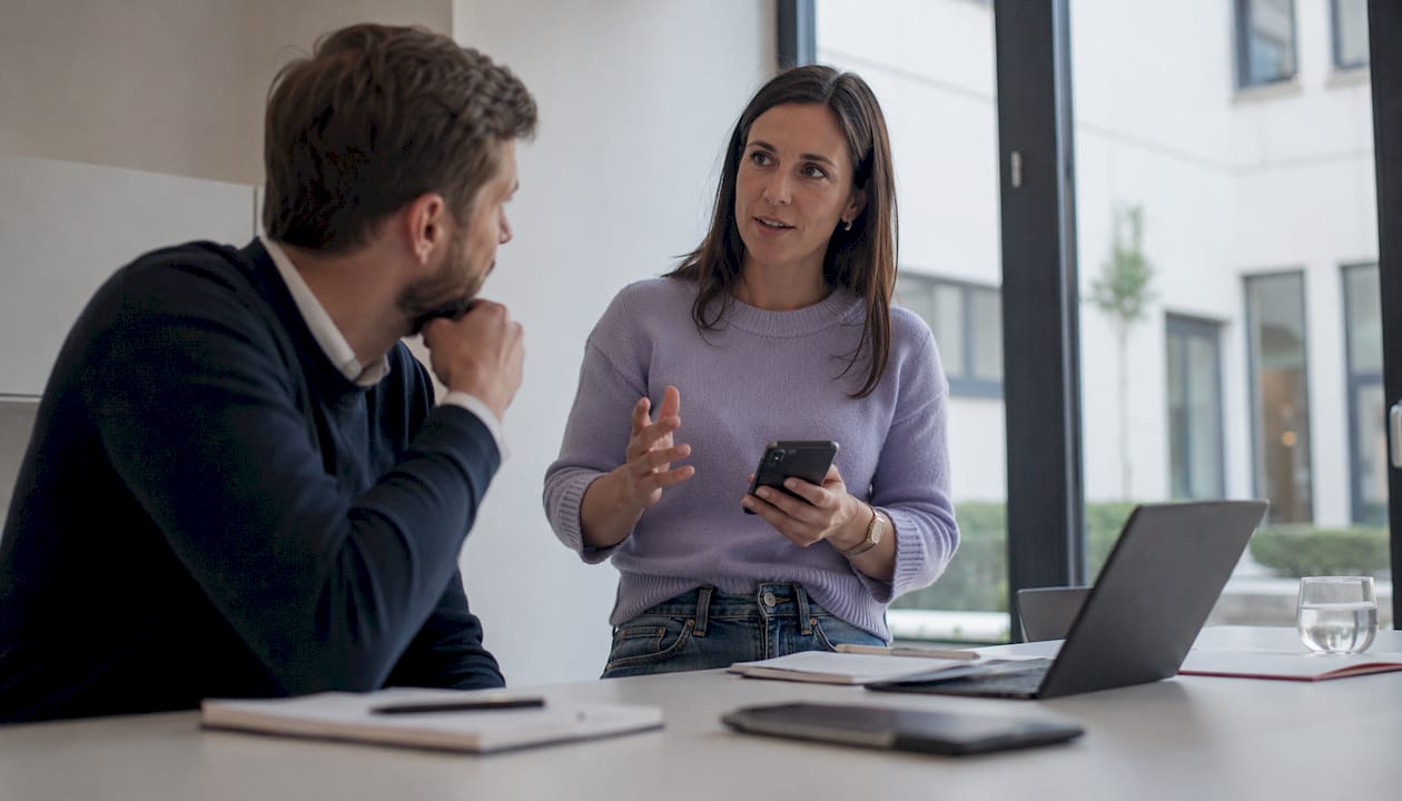 Ein Mitarbeiter der Agentur präsentiert auf seinem Smartphone die neue Webseite.