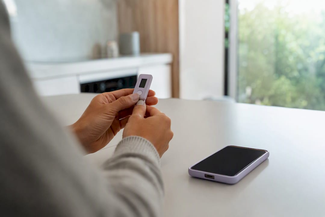 Hände halten ein Sicherheitstoken-Gerät nahe am Smartphone