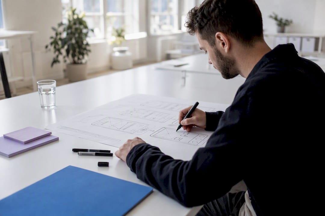 Hände zeichnen ein UI-Drahtmodell der App auf ein Whiteboard