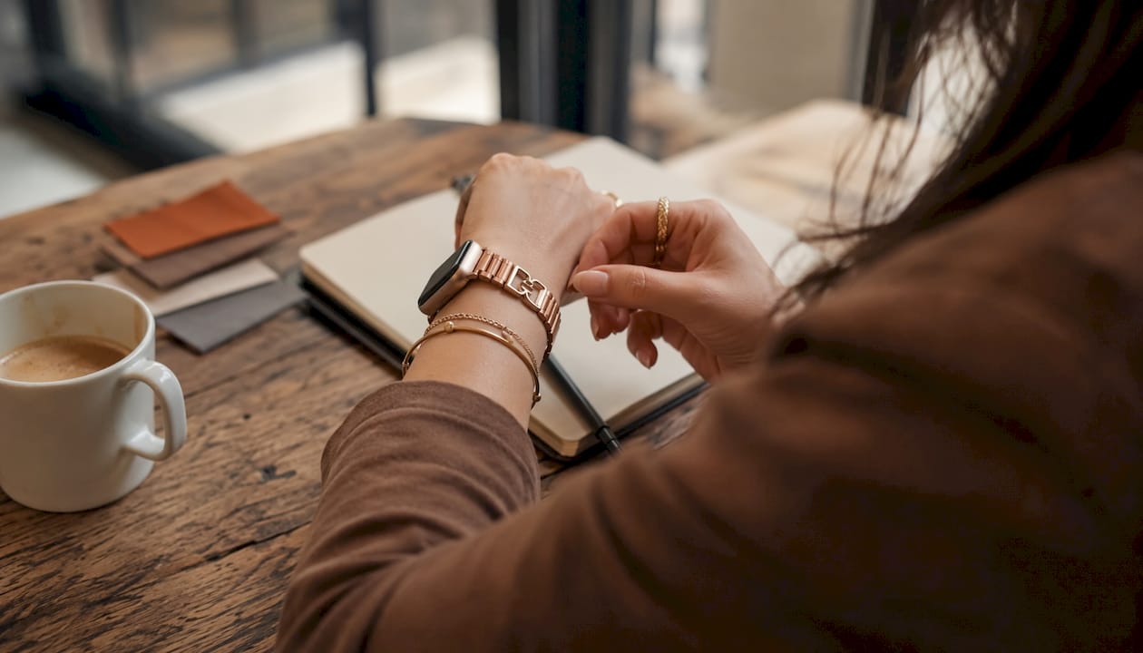 Close-up wrist with rose gold smartwatch and gold jewelry