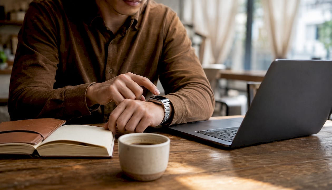 Professional using laptop wearing brushed metal watch band