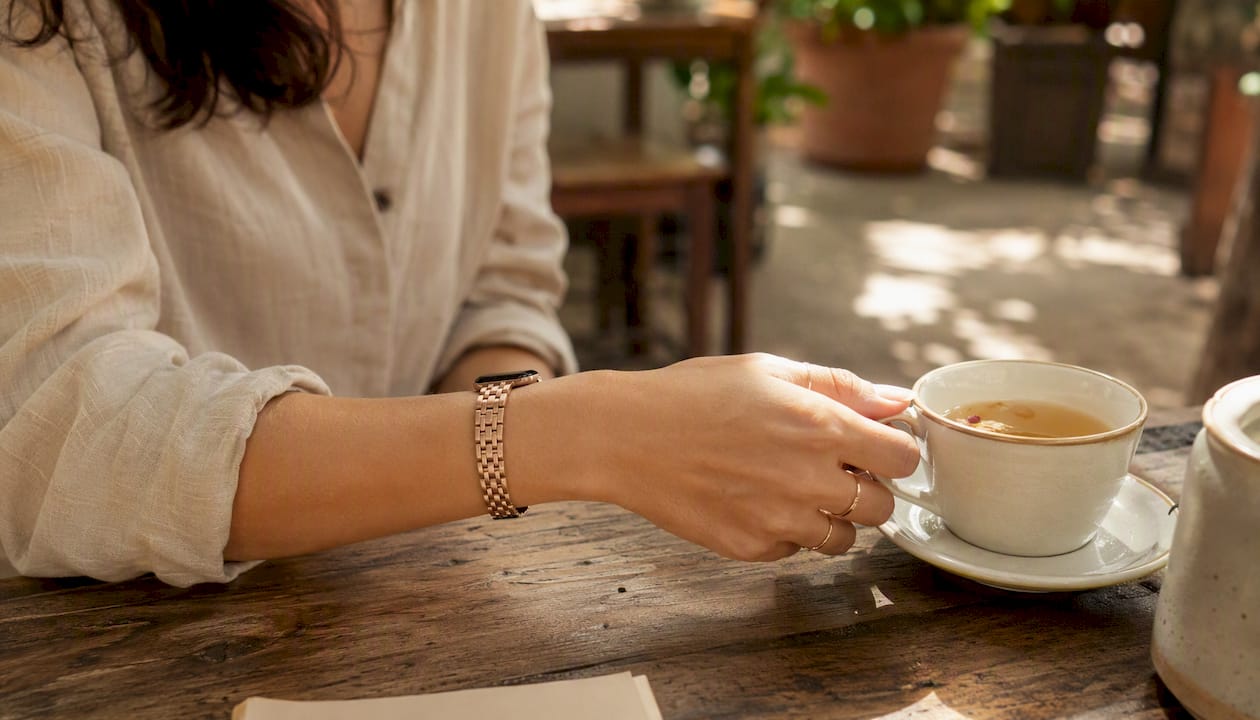 Wrist wearing rose gold band pouring tea