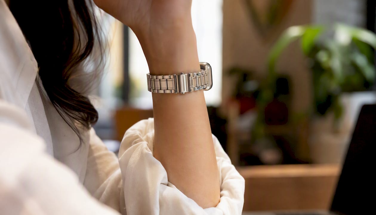 Silver gold metal Apple Watch band on wrist in office attire
