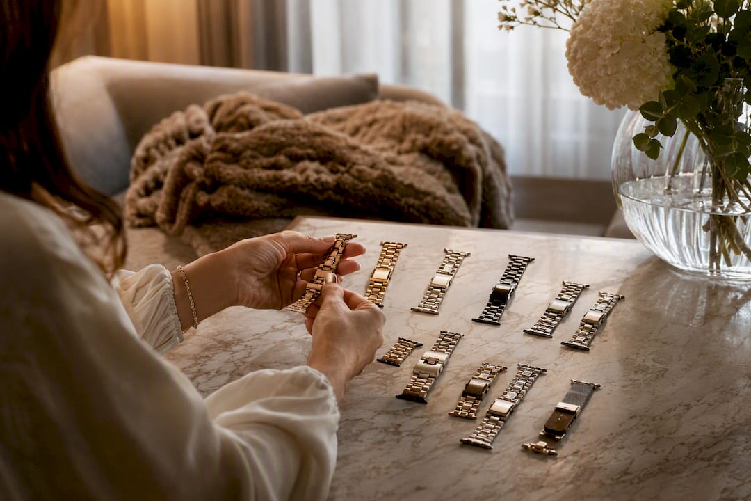 Hands arranging metal watch bands on vanity