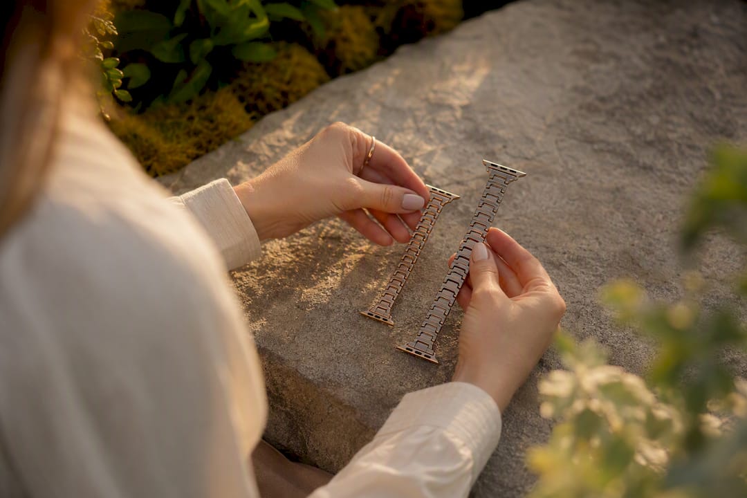 Hands comparing two metal Apple Watch band sizes