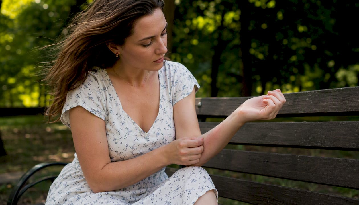 Woman checking skin redness after sun exposure