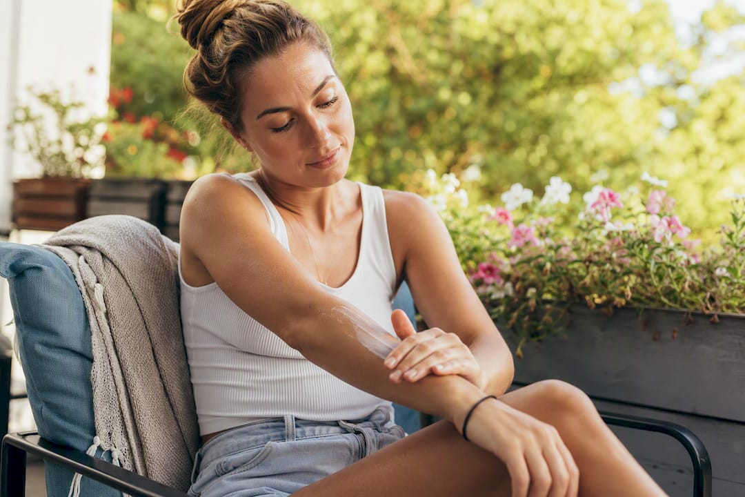 Woman applying sunscreen outdoors on arm
