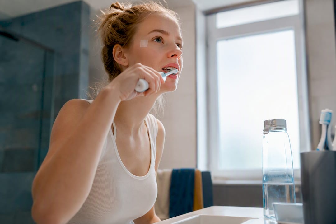 Woman brushing teeth with braces using electric toothbrush