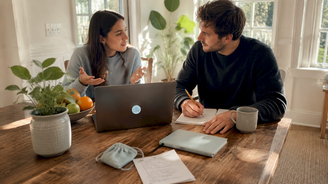 Couple planning bridesmaid jewelry budget at kitchen island