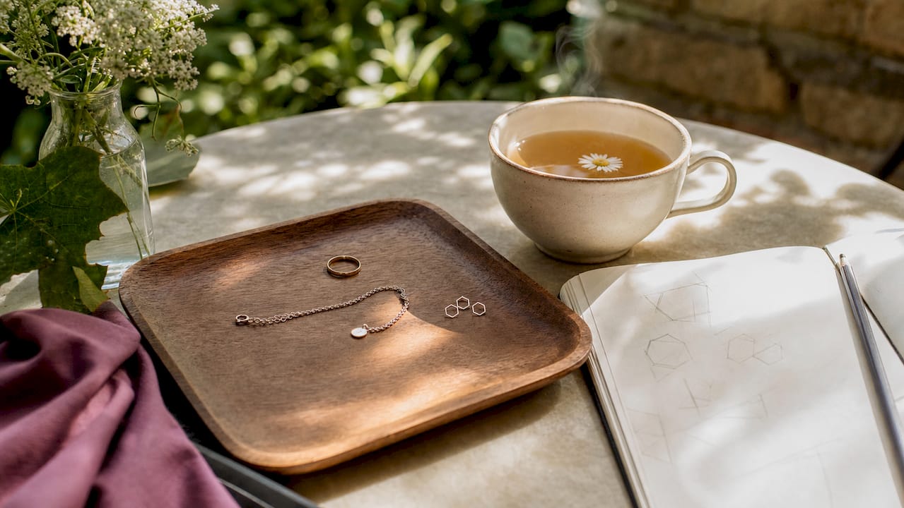 Minimalist jewelry pieces on marble tray with sketches