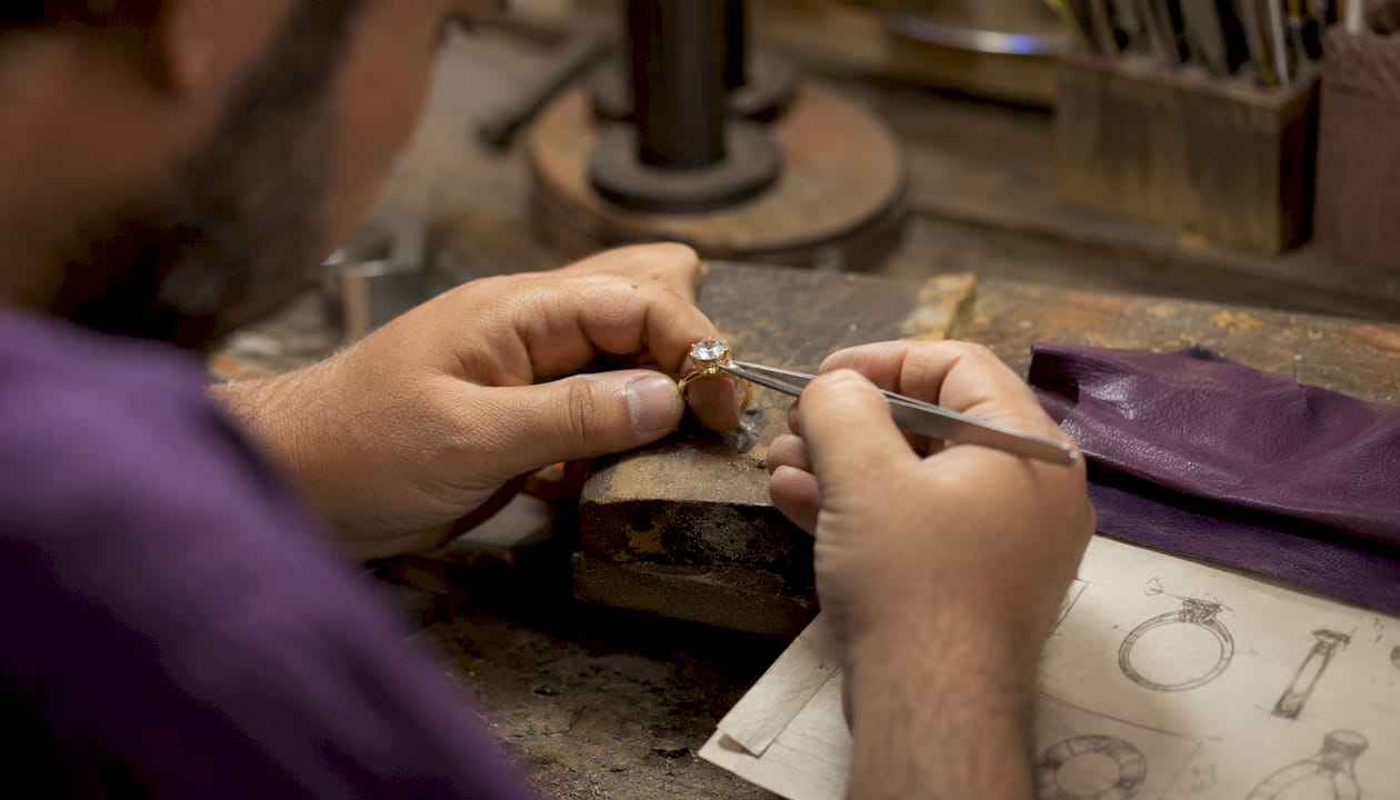 Artisan hands crafting moissanite ring at workbench