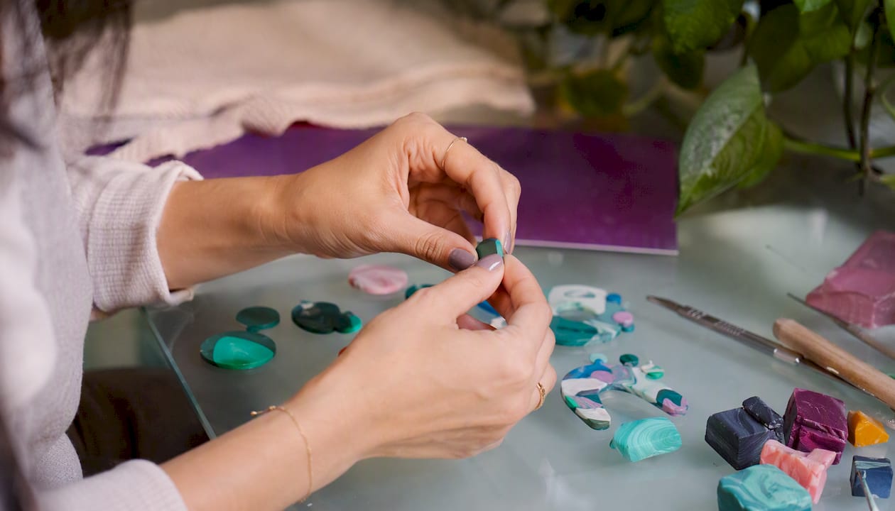 Hands shaping polymer clay earrings