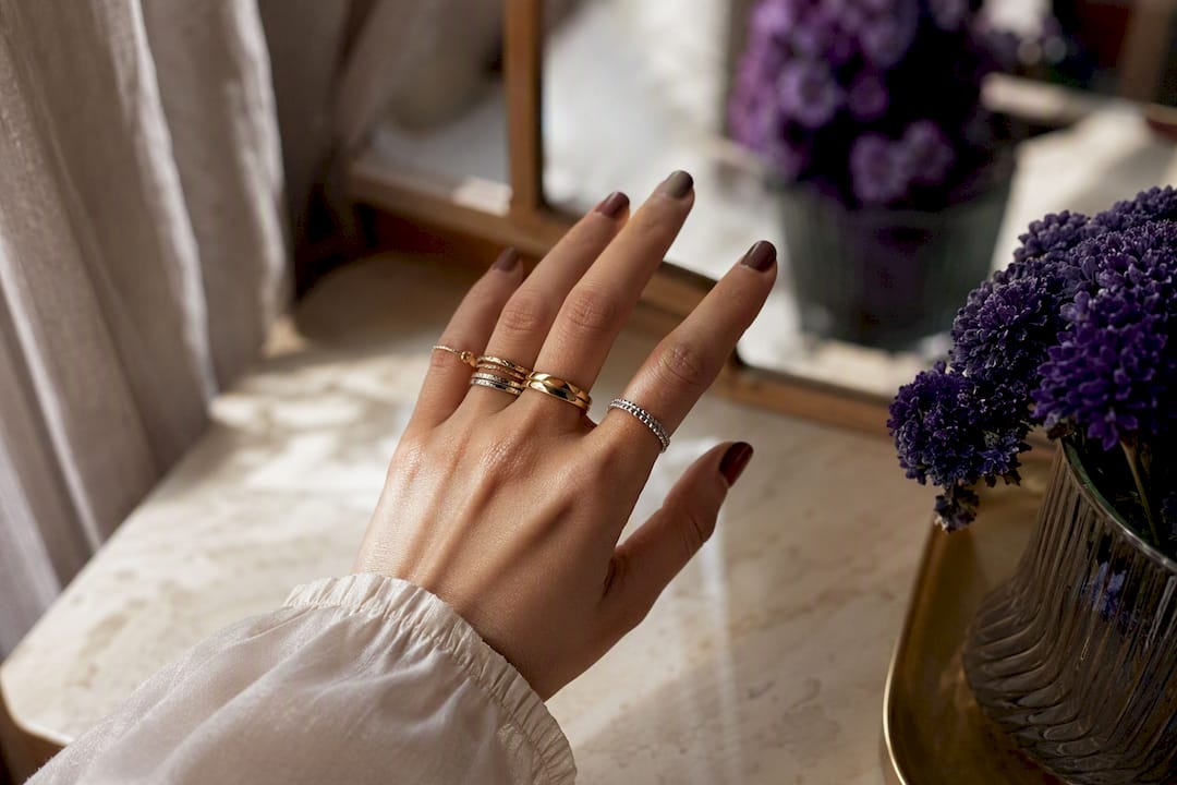 Stylish hands with rings and manicure on dressing table
