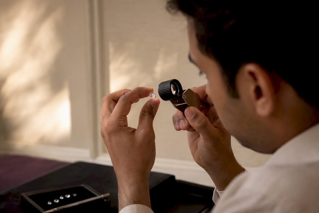 Hand holding moissanite gemstone with jeweler's loupe