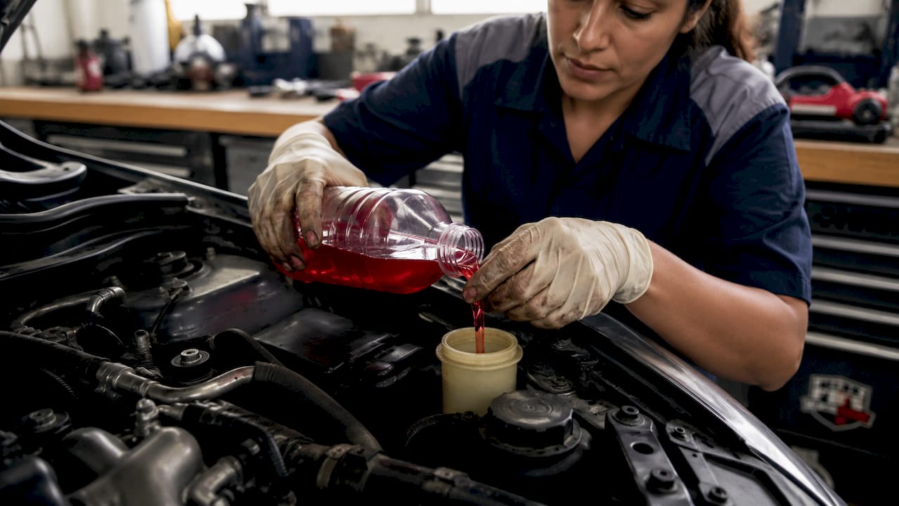 Hands pouring transmission fluid in garage