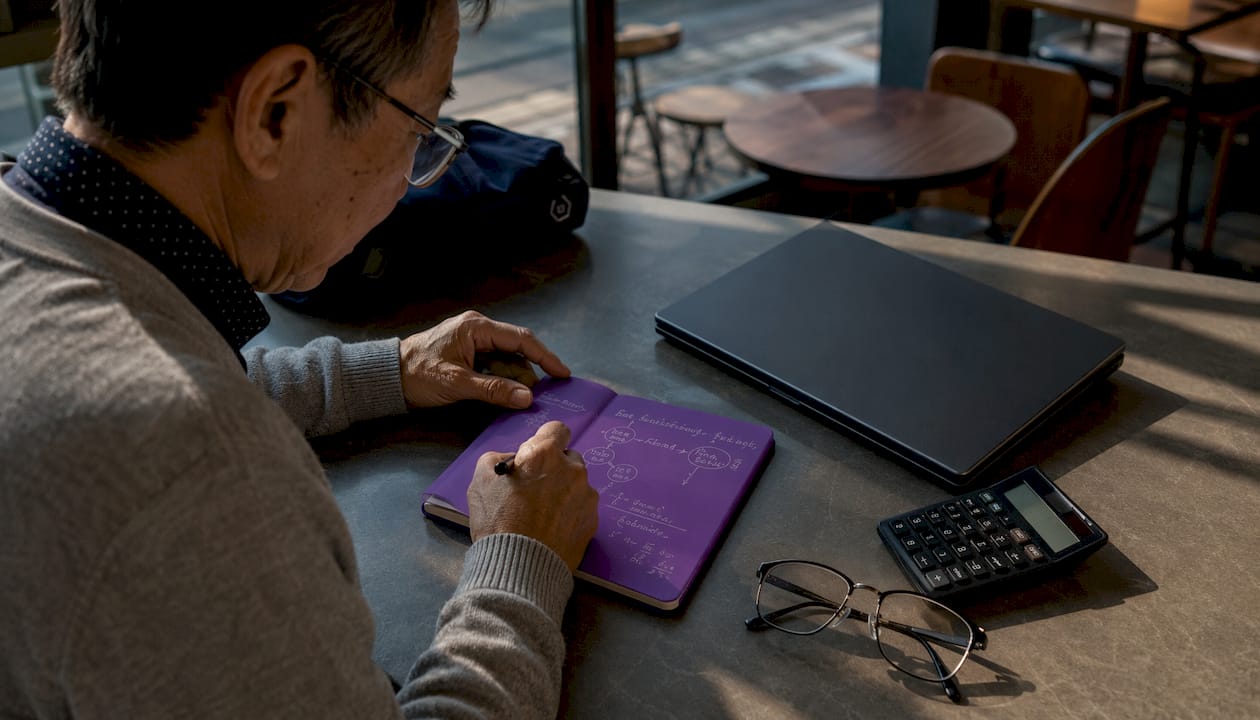 Hands writing marketing KPI formulas on notebook