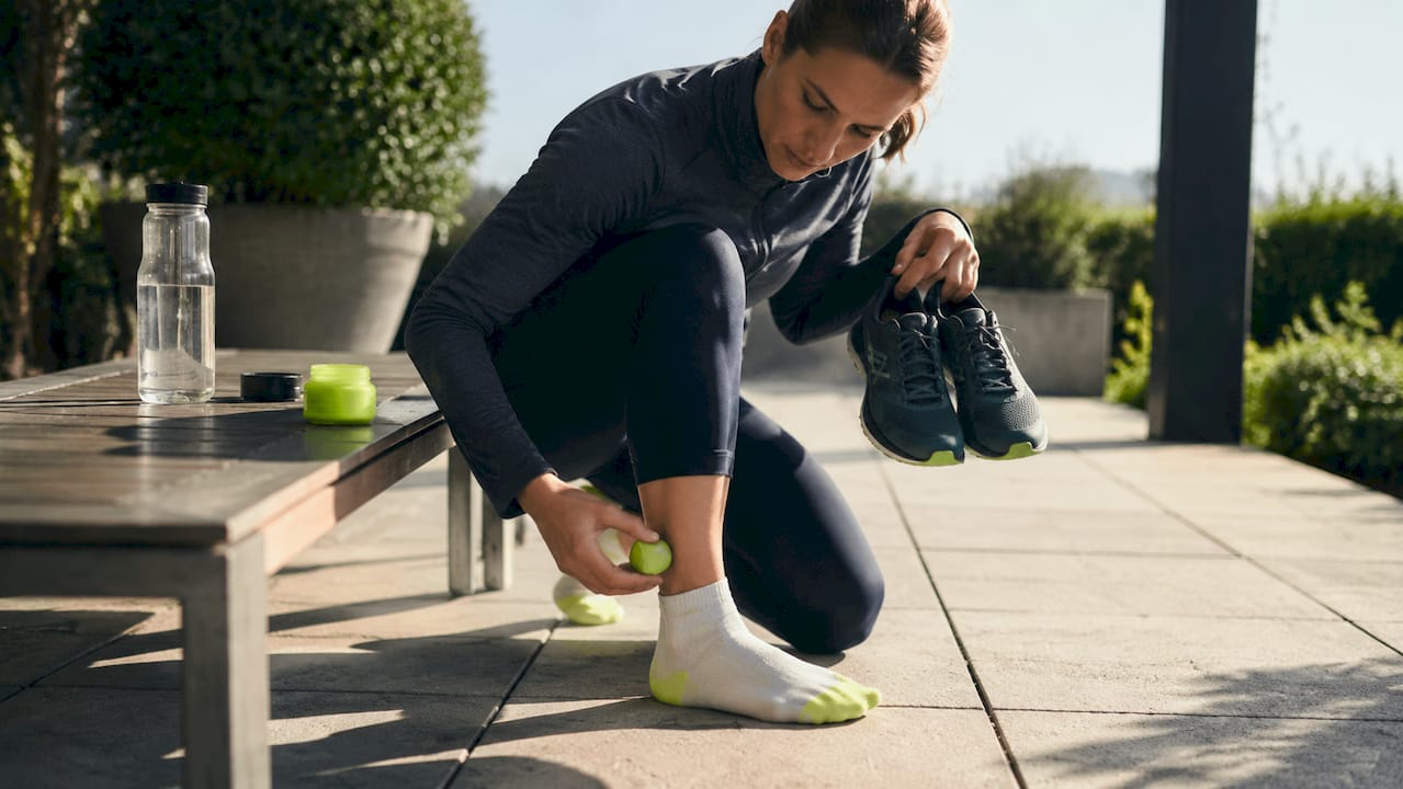 Close-up of runner adjusting socks and applying balm