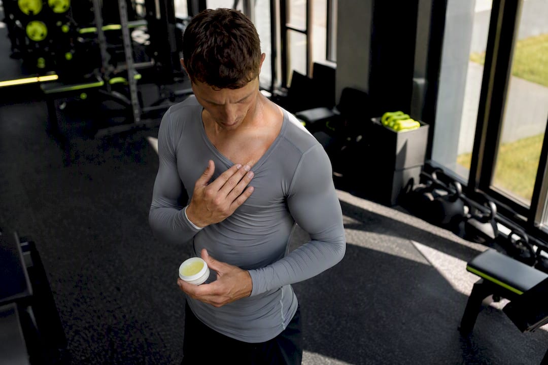 Hands applying anti-chafing balm on chest