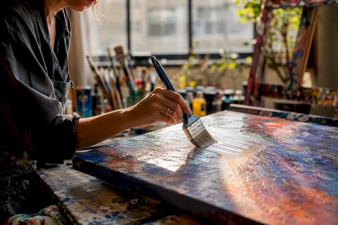 Artist brushing varnish on canvas
