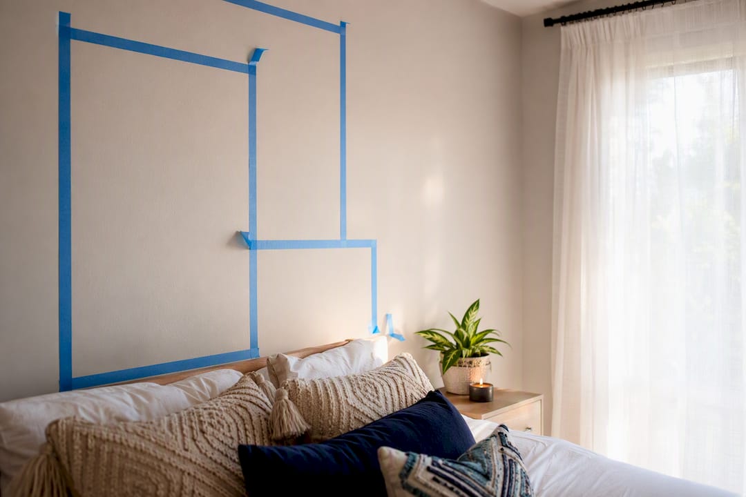 Painter's tape mockup on bedroom wall above bed
